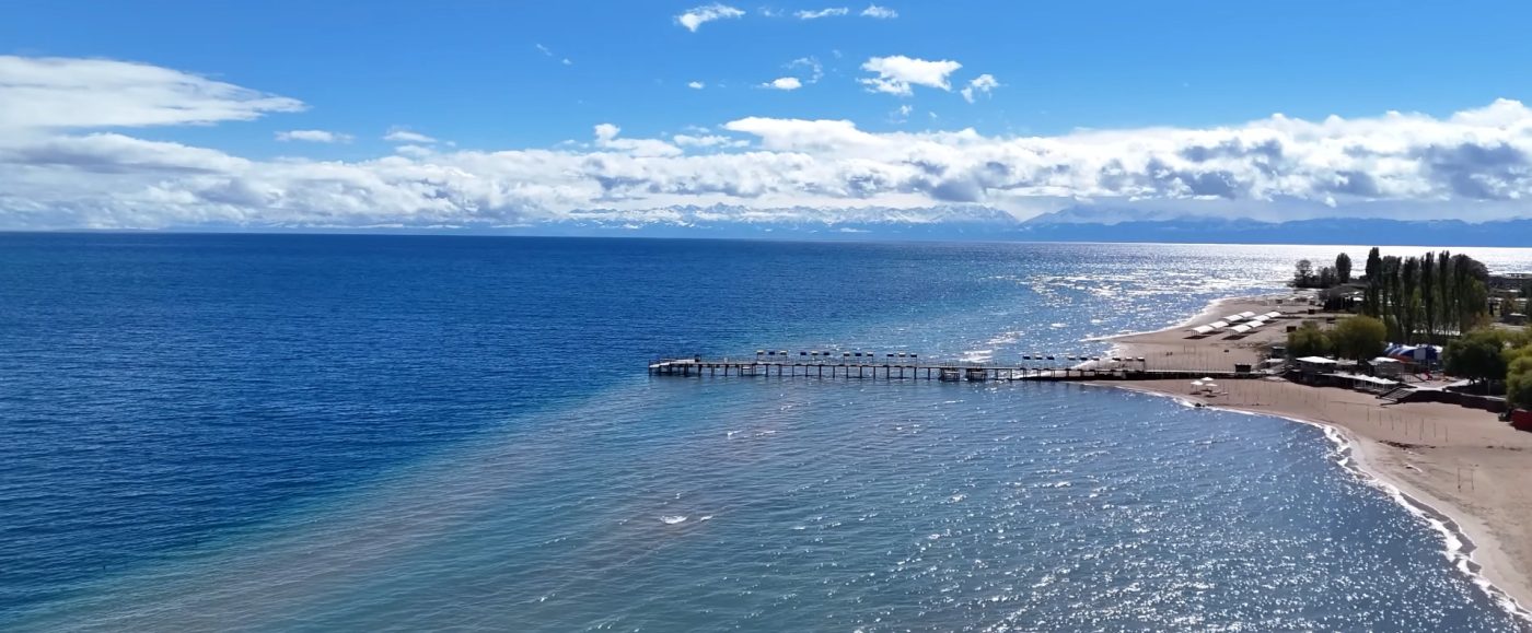 Wide landscape of Issyk Kul surrounded by alpine ridges and open sky