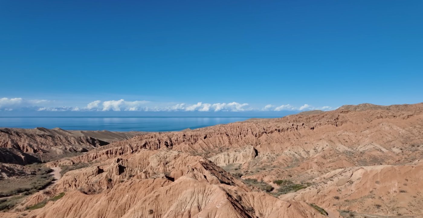 Turquoise Issyk Kul water framed by stones and shallow shoreline 